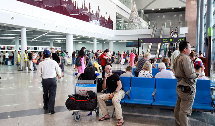 Des voyageurs cambodgiens et étrangers attendant devant les comptoirs d'enregistrement à l'aéroport de Phnom Penh