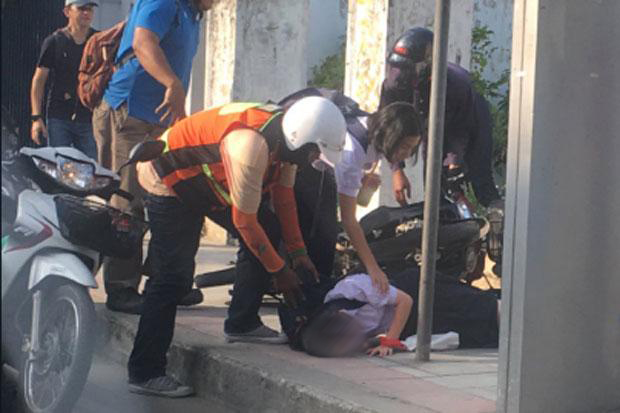 Des passants viennent en aide à une lycéenne renversée par un conducteur de scooter sur un trottoir de Lat Phrao Road à Bangkok