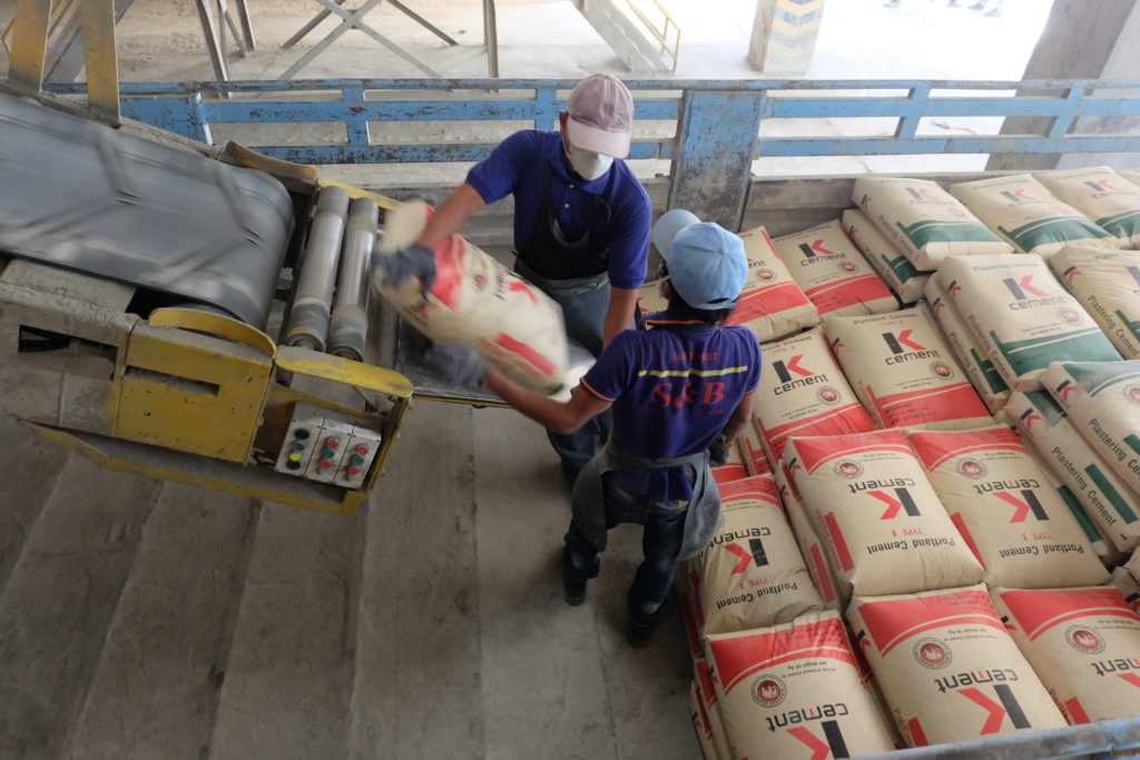 Workers at Siam Cement’s Cambodian plant in Kampot load plastering cement onto a truck